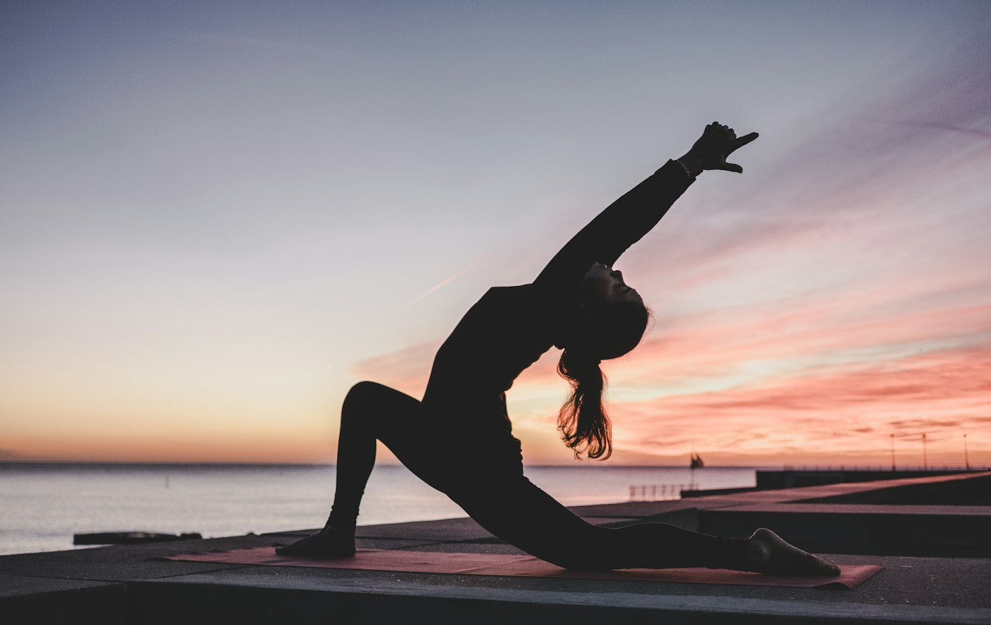 Practitioner holding a yoga pose at sunset